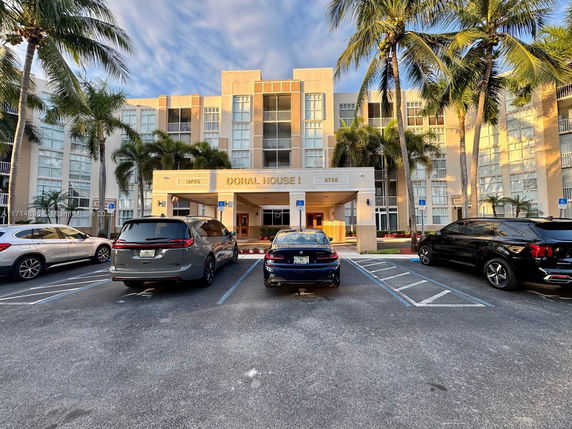 Front view of a multi-story building with large windows and palm trees.