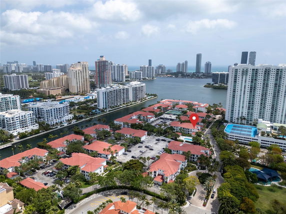 Panoramic view of a residential area with red-roofed buildings and tall high-rises near a water body.