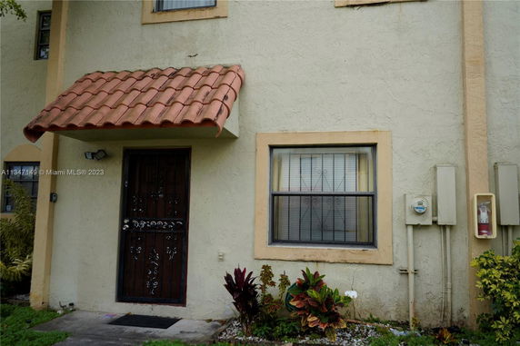 Front view of a house with a decorative metal door and a small tiled awning.