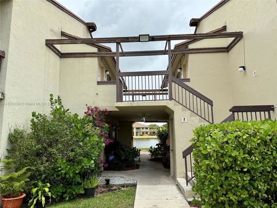 Front view of a multi-story building with an external staircase and greenery.