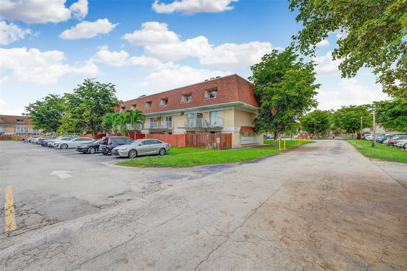 Outdoor parking area adjacent to a building with a sloped roof and multiple cars parked.