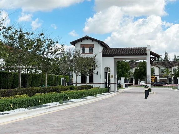 Front view of a two-story building with an arched entryway and tile roof.