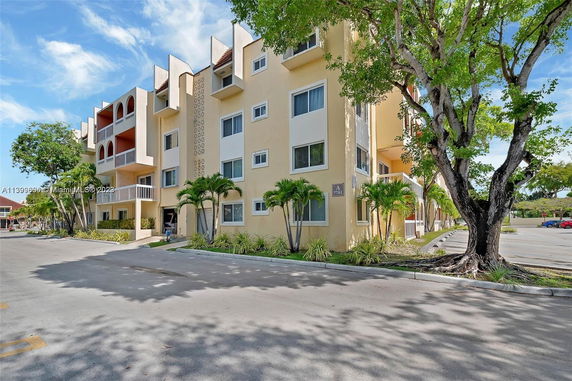 Front view of a multi-story residential building with balconies and beige exterior.