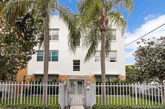 Front view of a multi-story building with white exterior and palm trees.