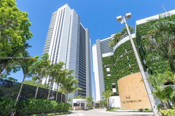 Front view of a tall residential building with modern architecture and green vertical walls.