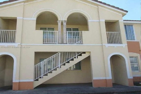 Front view of a two-story building with arches and a staircase.