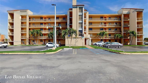 Front view of a multi-story residential building with balconies and parking area.