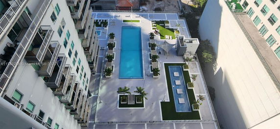 Rooftop area with swimming pool and greenery, adjacent to a multi-story building.