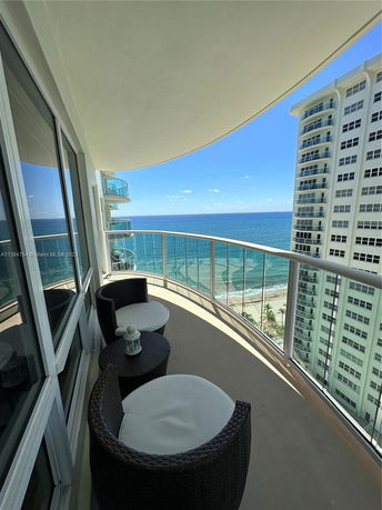 View from a curved balcony overlooking the ocean and nearby buildings.