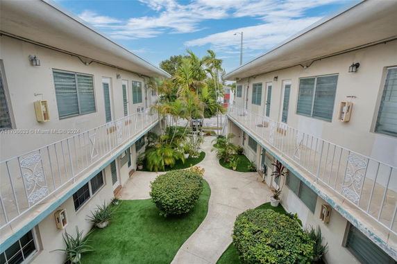 Front view of a two-story apartment building with balconies and landscaped greenery.
