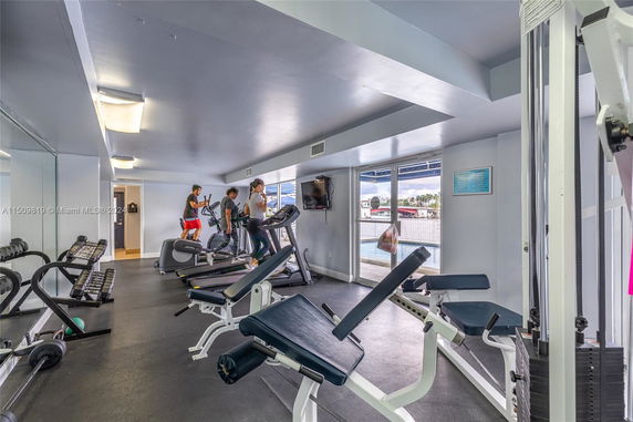 Indoor gym area with various exercise equipment and people working out.