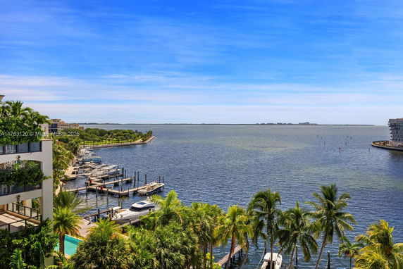 Panoramic view of a waterfront area with boats docked, surrounded by lush greenery and buildings.