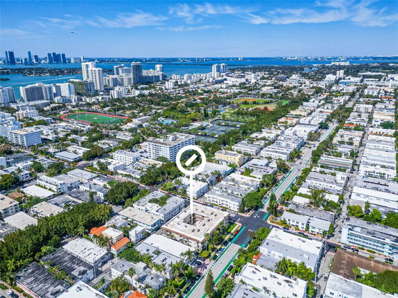 Aerial view of a cityscape featuring multiple buildings and a nearby body of water under a clear blue sky.