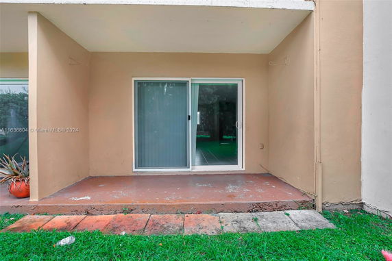 View of a building with a sliding glass door and small porch area.