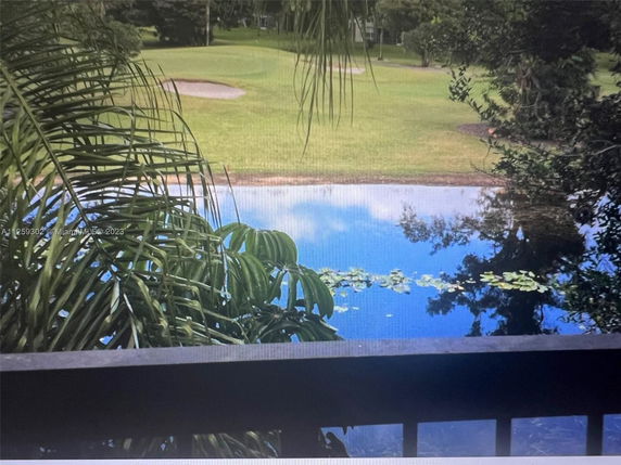 View of a lake with lily pads and a golf course