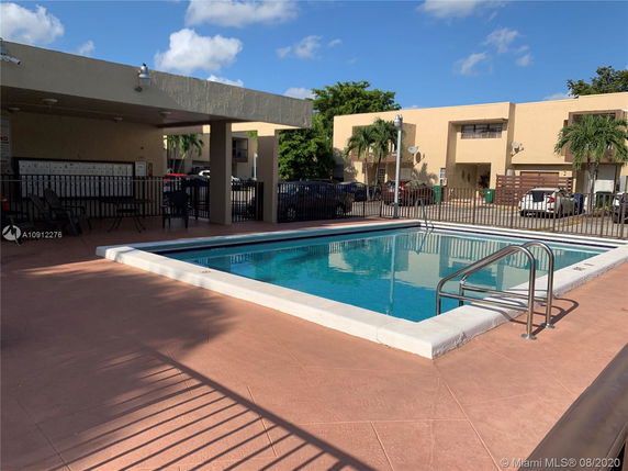 Outdoor swimming pool area with surrounding fence and seating.