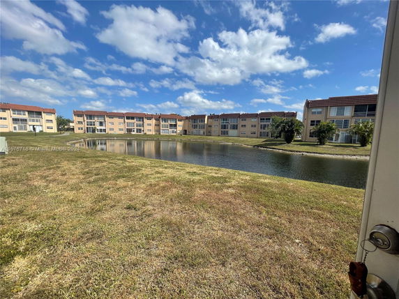 Buildings with multiple floors facing a water body with grassy area.