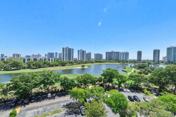 Panoramic view of a cityscape with high-rise buildings, a body of water, and green park areas.