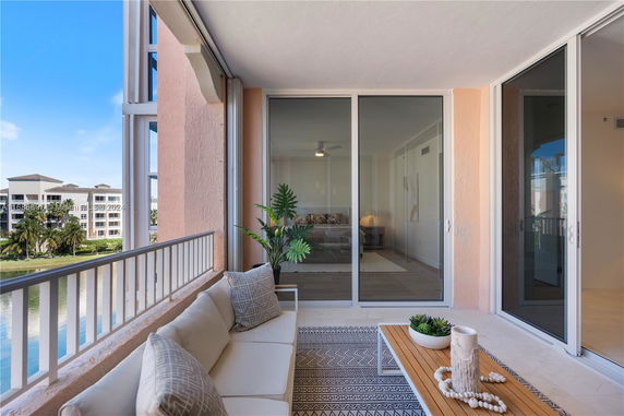 View from a balcony with outdoor seating overlooking residential buildings and greenery.