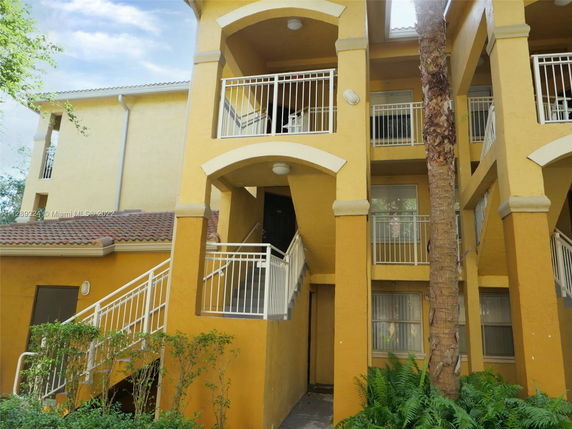 Front view of a multi-story building with balconies and stairs.