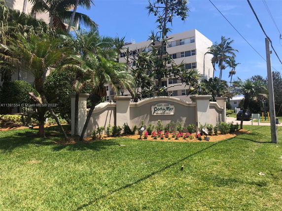 Front view of a multi-story building with a landscaped entrance and palm trees.