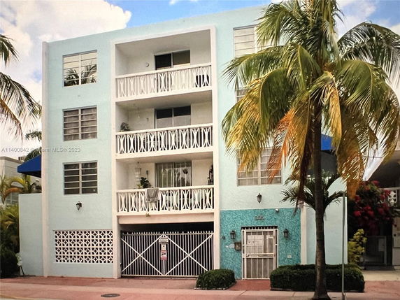 Front view of a multi-story building with balconies and a gated entrance.
