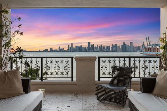 View from a balcony overlooking a city skyline across the water during sunset.