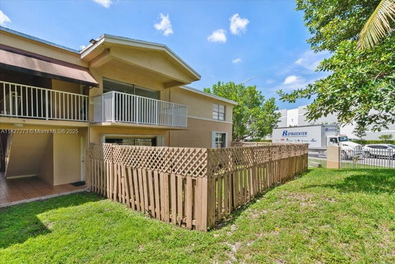 Front view of a two-story house with balconies and fenced yard.