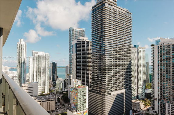 Panoramic view of tall skyscrapers with ocean in the background.