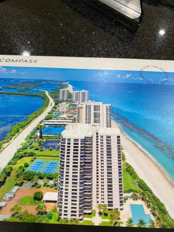 Aerial view of tall beachfront condominiums with tennis courts and swimming pools.