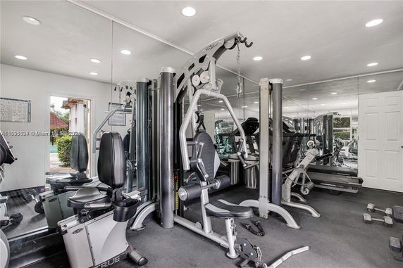 Room with various gym equipment and mirrors on the walls.