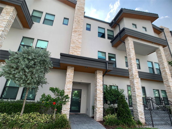 Front view of a multi-story modern building with stone accents and several windows.