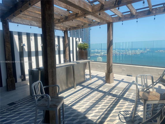 Rooftop with pergola, seating, and view of city skyline and water.