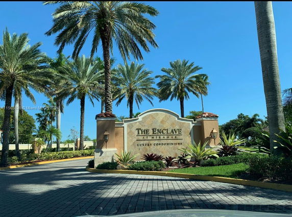 Entrance signage of a luxury condominium complex with palm trees.