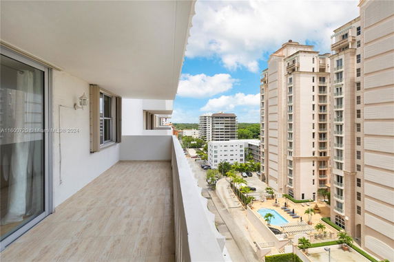 Panoramic view from a building balcony overlooking surrounding high-rise buildings and a swimming pool.