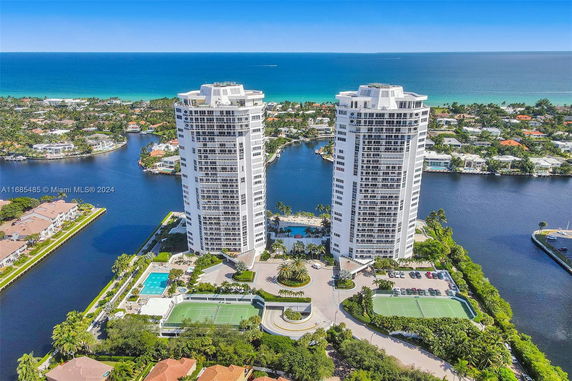 Aerial view of two high-rise residential buildings near a body of water with surrounding landscape.