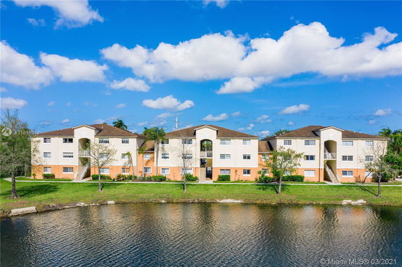 Front view of a three-story residential building near a water body.