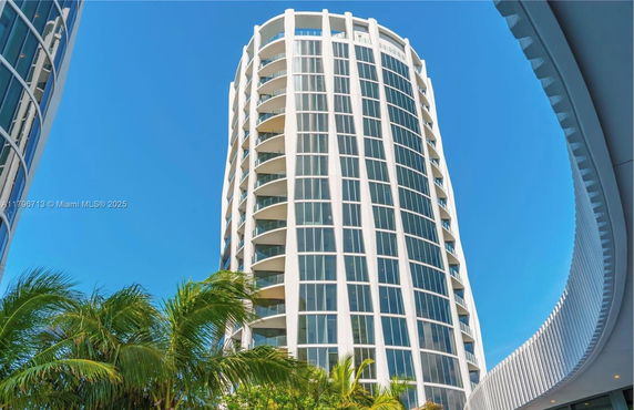 Front view of a tall, modern building with large windows and rounded architecture.