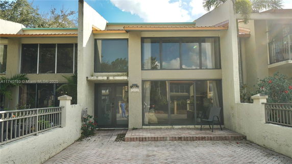 Front view of a two-story house with large windows and a paved driveway.