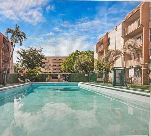 Outdoor swimming pool in front of a multi-story residential building.