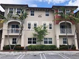Front view of a multi-story residential building with balconies and parking area.