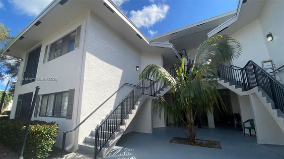 Front view of a two-story building with exterior staircases and a sloping roof.