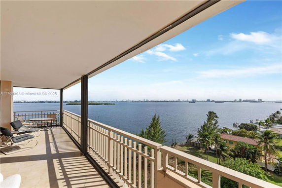 Wide angle view from a building balcony overlooking water and distant skyline.