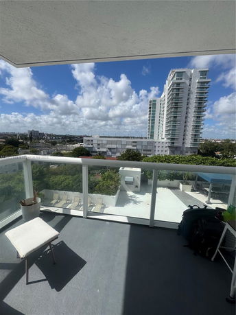 View from a balcony overlooking a cityscape with a tall building in the distance.