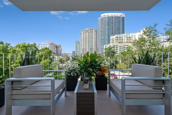 Balcony view with modern outdoor furniture overlooking city skyline.