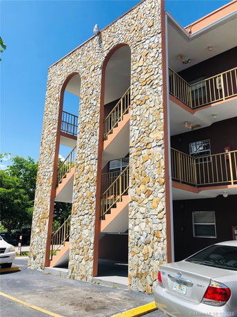 Front view of a multi-story building with stone facade and outdoor staircases.