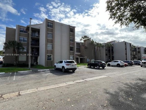Front view of a multi-story residential building with parking area.