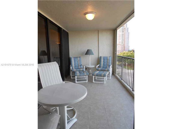Outdoor seating area on a balcony with chairs and a table.