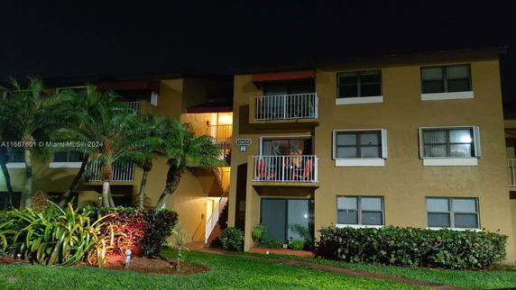 Night view of a three-story apartment building with balconies.