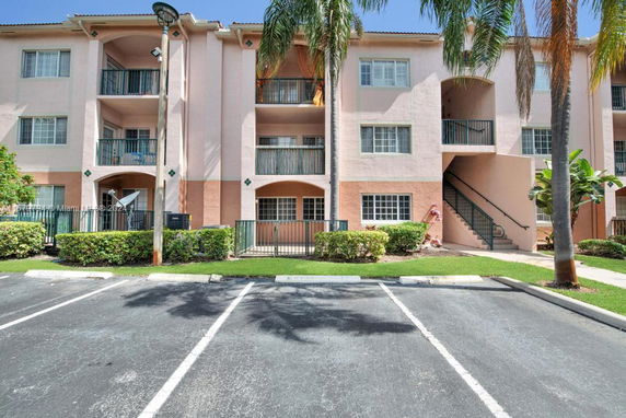Front view of a multi-story residential building with balconies and parking area.
